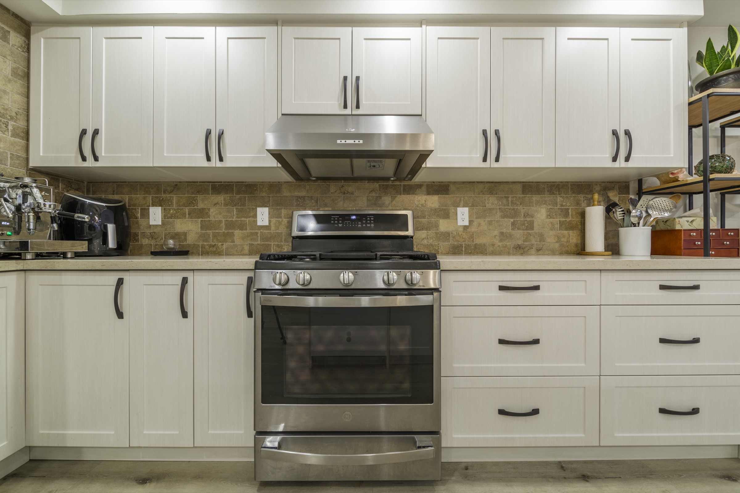 White cabinets with dark handles above a range and tan tiled backsplash