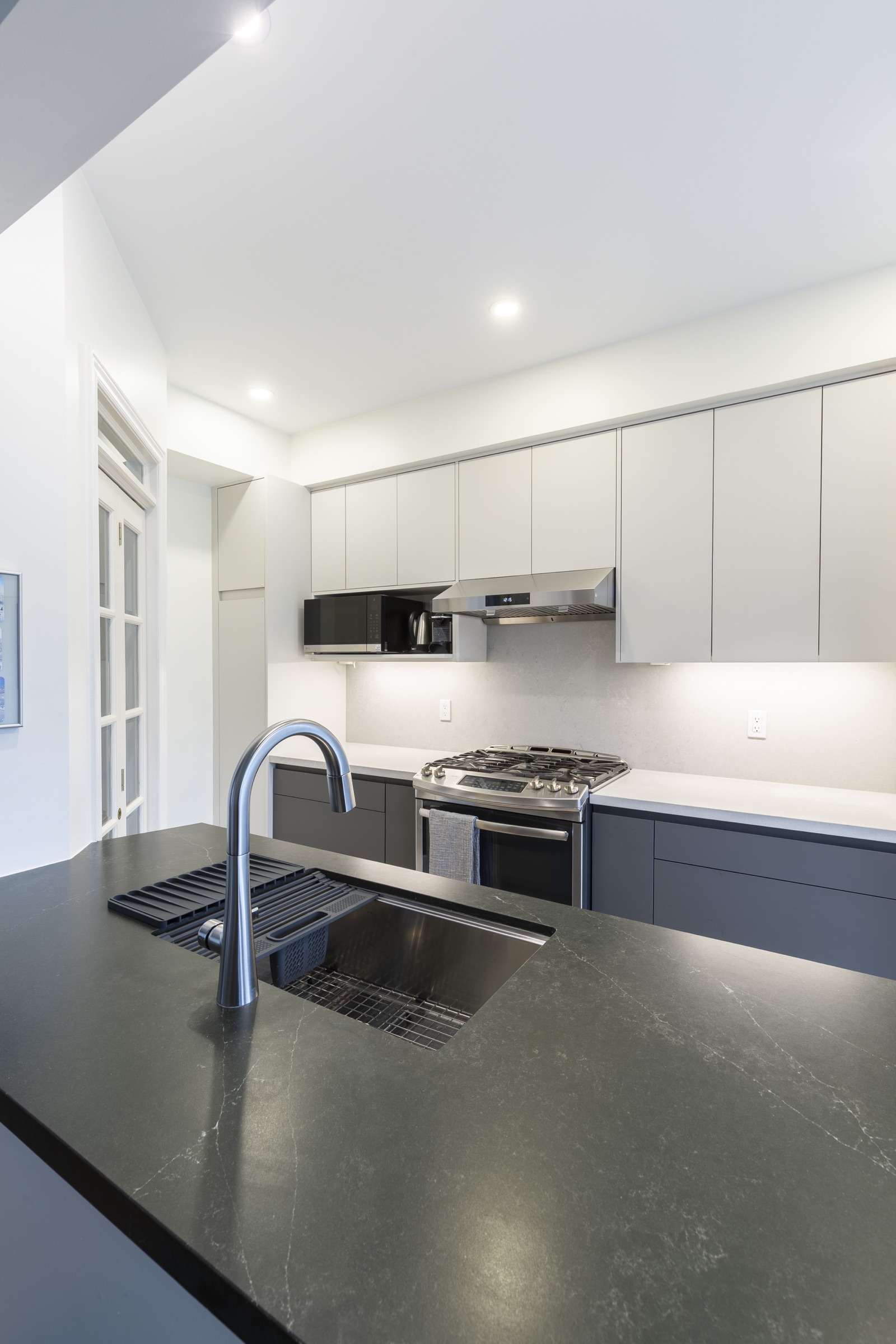 Flat-front kitchen cabinets beside a dark countertop and sink