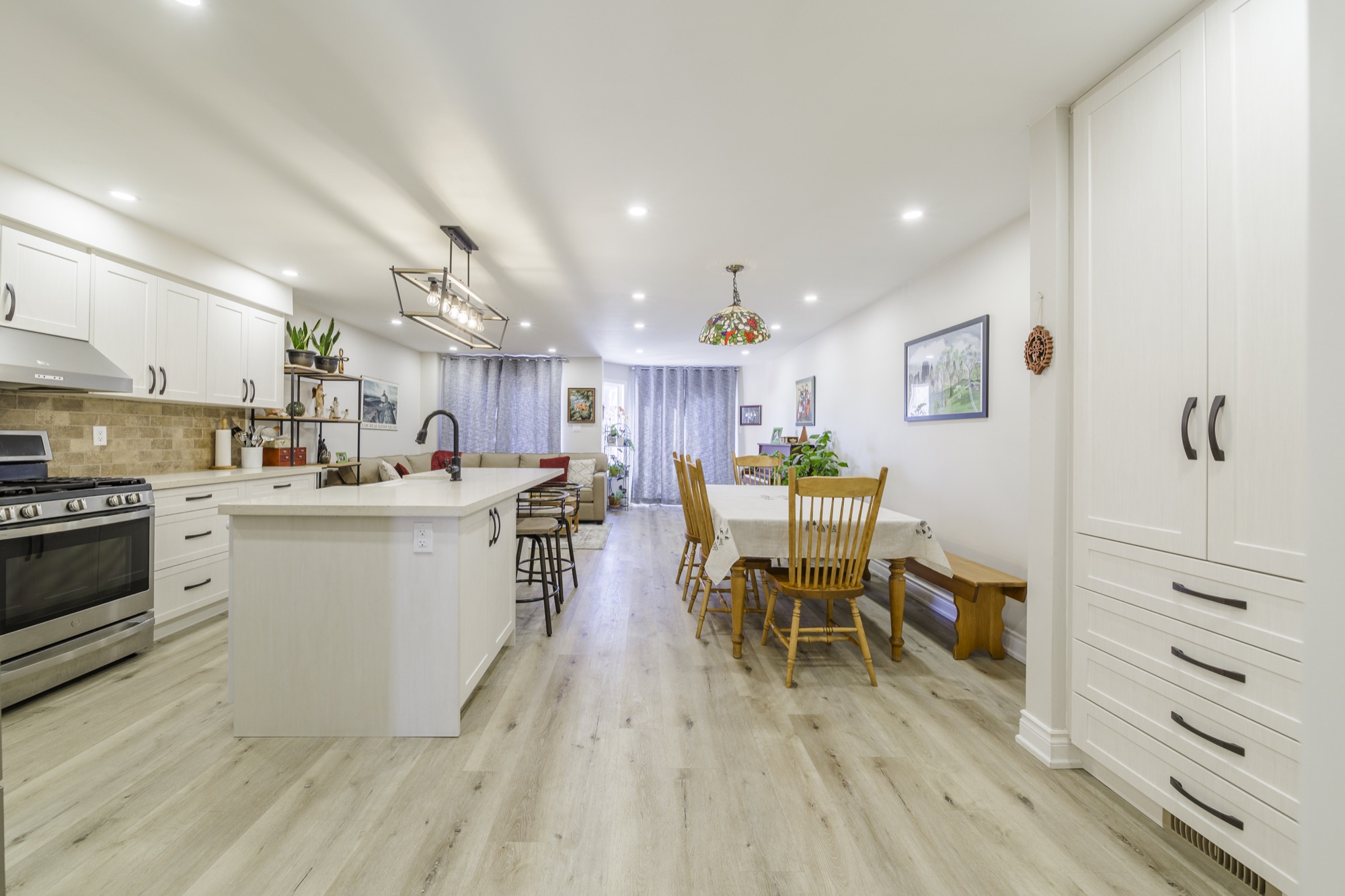Kitchen island beside full-height storage, with dining and living space beyond