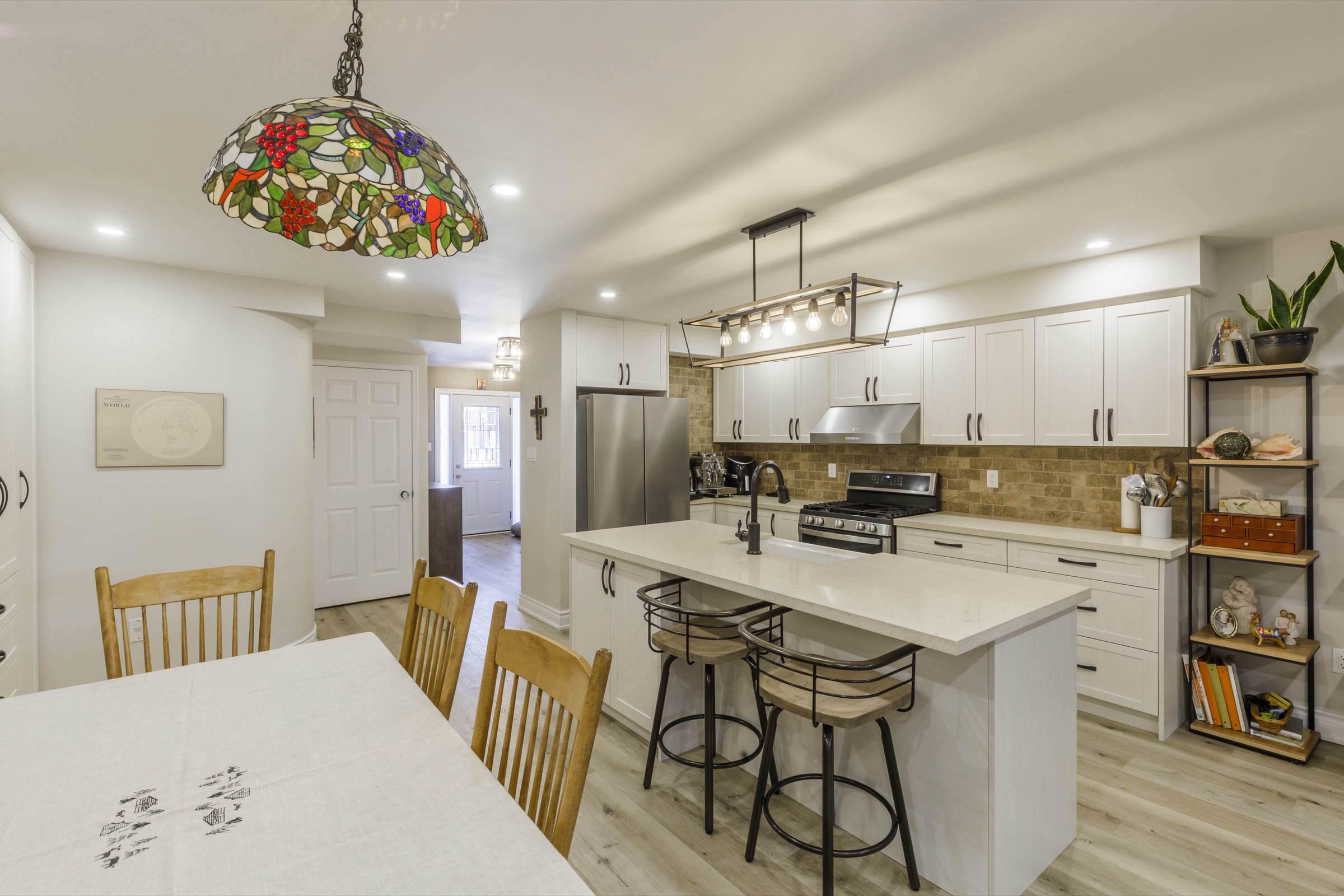 White kitchen cabinetry with a tan backsplash and counter seating