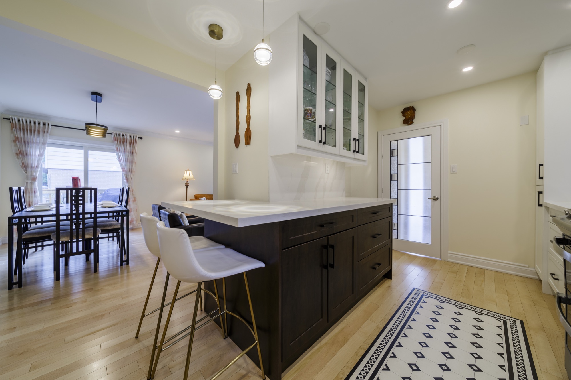 Dark kitchen drawers, pale countertop and glass-front cupboards beside counter seating